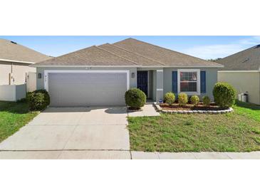 One-story house with gray siding, two-car garage, and landscaped yard at 417 Pinecrest Loop, Davenport, FL 33837