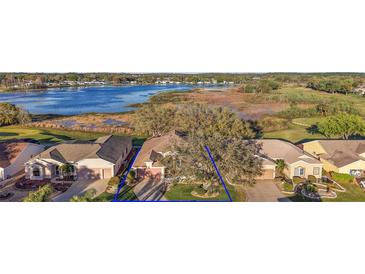 Aerial view of a charming single Gathering home with lush landscaping, a lake, and golf course views at 4822 Sawgrass Lake Cir, Leesburg, FL 34748