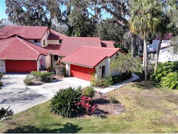 Aerial view of Spanish-style home with red tile roof and lush landscaping at 601 Waterwood Dr, Yalaha, FL 34797