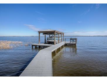 Private boat dock with covered boathouse on a calm lake at 908 N Lakeshore Blvd, Howey In The Hills, FL 34737