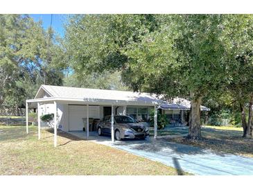 Charming single-story home featuring a covered carport and mature trees at 11221 Lake Eustis Dr, Leesburg, FL 34788