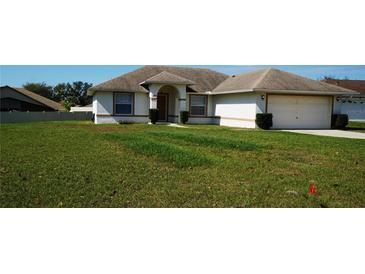 Charming single-story home with a well-manicured front lawn, inviting entrance, and attached garage at 137 Country Lakes Cir, Groveland, FL 34736