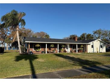 Brick ranch house with covered porch, large yard, and waterfront views at 1401 Lake Shore Blvd, Tavares, FL 32778