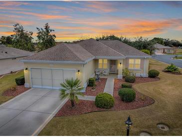 Single-story home with a screened garage and landscaped yard at sunset at 14267 Se 85Th Ter, Summerfield, FL 34491