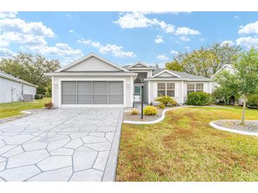 Single-story home with gray siding, a two-car garage, and a stone driveway at 2123 Barbosa Ct, The Villages, FL 32159