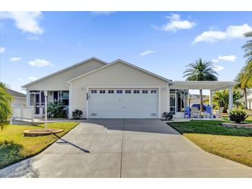 Beige house with a two-car garage and a covered patio at 2214 Quinn Ln, The Villages, FL 32162