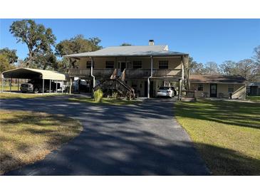 Two-story home with large deck, carport, and detached building at 2403 County Road 416N, Lake Panasoffkee, FL 33538