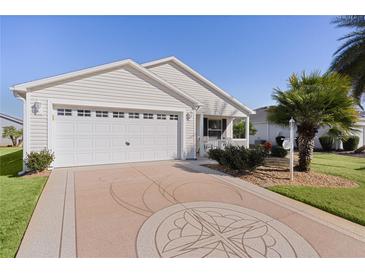 White house with two-car garage, palm trees, and landscaped yard at 2565 Edenville Path, The Villages, FL 32162