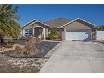 Tan one-story house with a two-car garage and landscaped yard at 2775 Sw 158Th St, Ocala, FL 34473