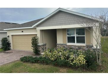 One-story home with a beige exterior, stone accents, and a two-car garage at 29567 Caspian St, Leesburg, FL 34748