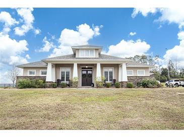 Single-story home with stone accents and a large front porch at 41516 Saddle Ridge Ln, Weirsdale, FL 32195