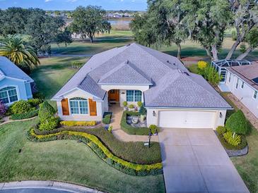 Single-story home with a two-car garage, lush landscaping, and golf course views at 581 Society Hill Cir, The Villages, FL 32162