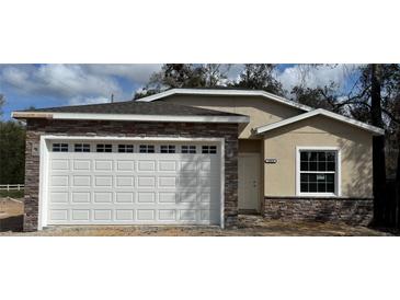 Charming home featuring a brick facade, a two-car garage, and a well-manicured front yard at 19020 Cr-450, Umatilla, FL 32784