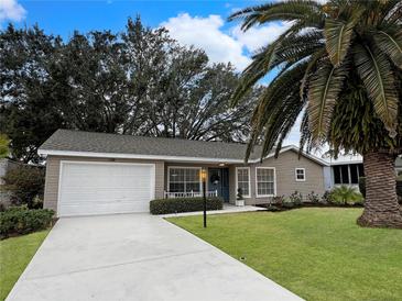 Tan house with a blue door, palm trees, and a well-manicured lawn at 25141 Clifford Hl, Leesburg, FL 34748
