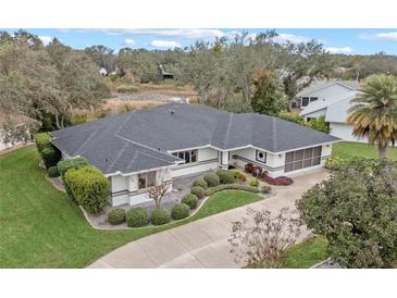 Single-story home with gray roof, white walls, and landscaped yard near a lake at 27010 Racquet Cir, Leesburg, FL 34748