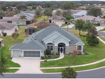 One-story house with a gray roof, light green exterior, and a two-car garage at 27504 Stoney Brook Dr, Leesburg, FL 34748