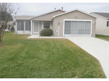 Tan one-story house with 2-car garage and well-maintained lawn at 3243 Mansfield St, The Villages, FL 32162