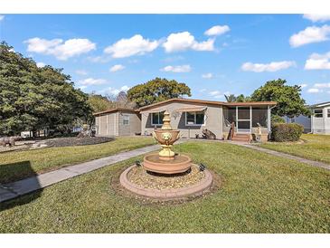 Single-story home with landscaped yard, fountain, and shed at 34205 Island Dr, Leesburg, FL 34788