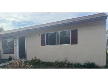 Tan house with burgundy shutters, a single door entry, and small landscaping at 516 E Rosewood Ln # 516, Tavares, FL 32778