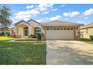 Single-story house with a two-car garage and landscaped lawn at 5616 Illumination Ln, Leesburg, FL 34748