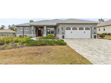 Gray house with white garage door, landscaped yard, and a paved driveway at 9287 Sw 102Nd Avenue Rd, Ocala, FL 34481