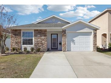 Charming single-Gathering home featuring a stone facade, well-maintained lawn, and attached garage at 12306 Ne 48Th Way, Oxford, FL 34484