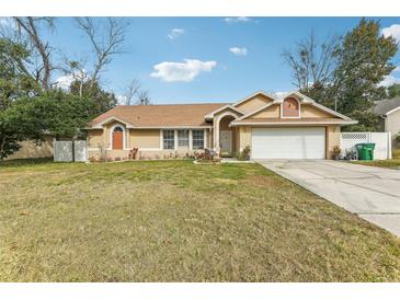 Tan house with a two-car garage and well-maintained lawn at 1381 Winterville St, Deltona, FL 32725