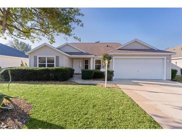 Beige house with a two-car garage and well-manicured lawn at 17030 Se 79Th Clearview Ave, The Villages, FL 32162