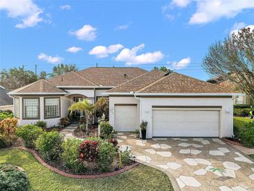 Charming home featuring manicured landscaping, a three-car garage, and a decorative driveway at 17430 Se 115Th Terrace Rd, Summerfield, FL 34491