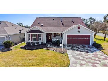 Single-story home with a red door and patterned driveway at 2762 Morven Park Way, The Villages, FL 32162