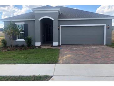 Gray house with two-car garage and landscaped yard at 2848 Supermarine Rd, Tavares, FL 32778