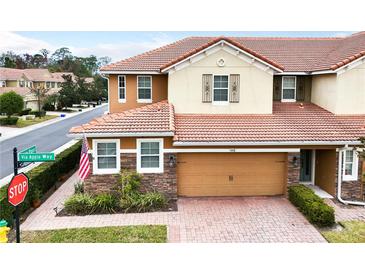 Two-story townhome with a large driveway, an American flag, and nicely landscaped yard at 5448 Via Appia Way, Sanford, FL 32771