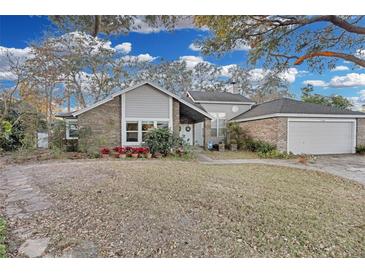 Two-story house with gray siding, brick accents, and a two-car garage at 7798 Snowberry Cir, Orlando, FL 32819