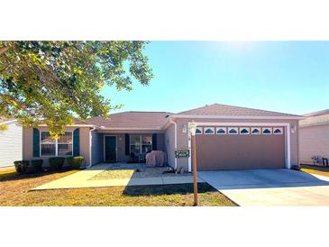 One-story home with a beige exterior, two-car garage, and landscaped yard at 9616 Se 168Th Elderberry Pl, The Villages, FL 32162