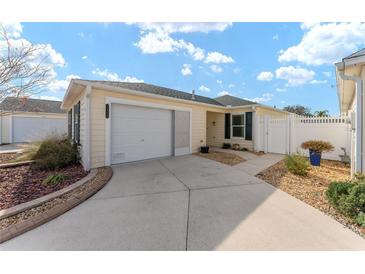 Light yellow house with white garage door, landscaped yard, and walkway at 1410 Conchas Dr, The Villages, FL 32162