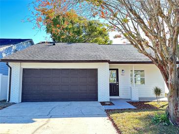 Newly renovated home with white exterior, brown garage door, and landscaped yard at 1562 Lawndale Cir, Winter Park, FL 32792