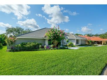 Gray brick home with manicured lawn, landscaping, and flowering crape myrtle tree at 365 N Spaulding Cv, Lake Mary, FL 32746