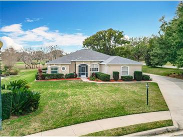 Charming single-story home with a manicured lawn, landscaped garden beds, and a circular driveway in a serene neighborhood at 39656 Harbor Hills Blvd, Lady Lake, FL 32159