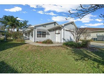 Charming single-story home featuring light blue siding, an attached garage, and a well-maintained lawn at 7 Ginger Cir, Leesburg, FL 34748