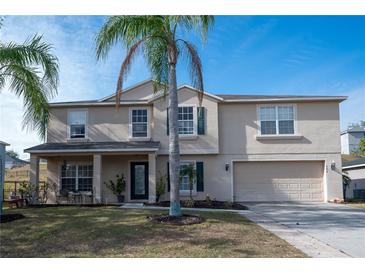 Two-story house with tan exterior, two-car garage, and palm trees at 702 Skyridge Rd, Clermont, FL 34711