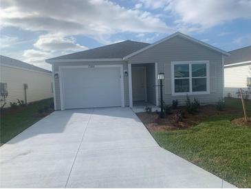 Newly constructed home with a white garage door and landscaping at 7268 Annison Ter, The Villages, FL 32163