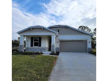 One-story home with gray siding, stone accents, and a two-car garage at 10161 Spring Lake Dr, Clermont, FL 34711