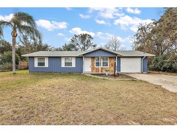 Ranch style home with blue siding, stone accents, and a two-car garage at 10830 Anna Belle Ave, Leesburg, FL 34788