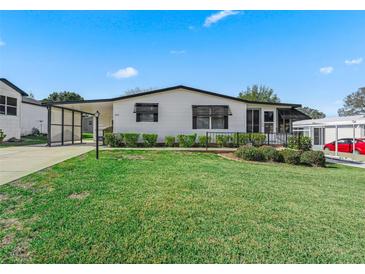 White single-story home with carport, landscaping, and a spacious lawn at 1210 Tarpon Ln, The Villages, FL 32159