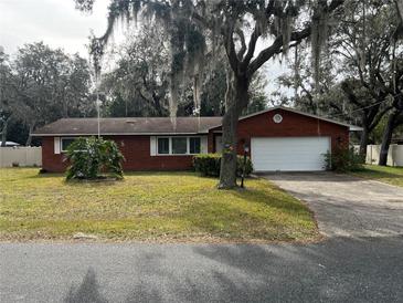 Charming brick home with a well-maintained lawn and mature trees draped with Spanish moss at 1511 Spanish Ave, Leesburg, FL 34748