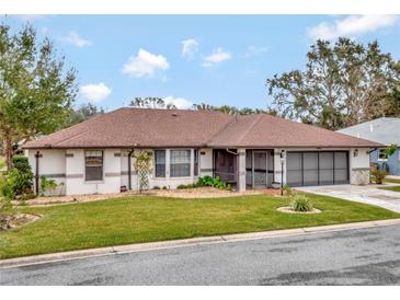 Single-story home with brown roof and landscaped lawn at 21524 Queen Anne Ct, Leesburg, FL 34748