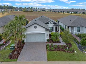 Single-story home with gray siding, a large driveway, and landscaping at 2597 Mariotta Rdg, Clermont, FL 34715