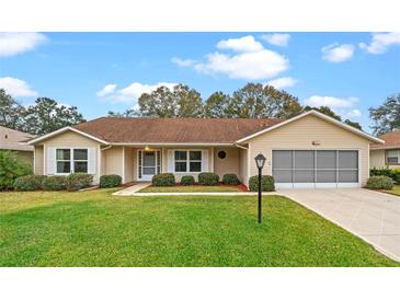 Tan one-story house with brown roof, landscaping, and a screened garage at 26913 Racquet Cir, Leesburg, FL 34748