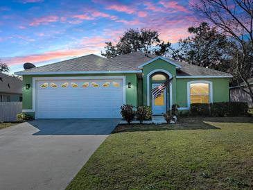 Green house with a white garage door, landscaping, and American flag at 30111 Pga Dr, Mount Plymouth, FL 32776