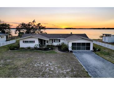 Aerial view of a single-story home with lakefront access and sunset views at 33648 Picciola Dr, Fruitland Park, FL 34731